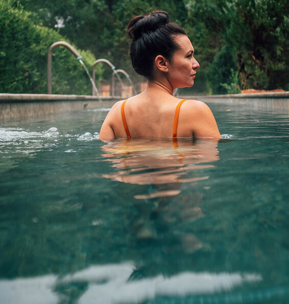 Person in a hotel pool with greenery in the background.